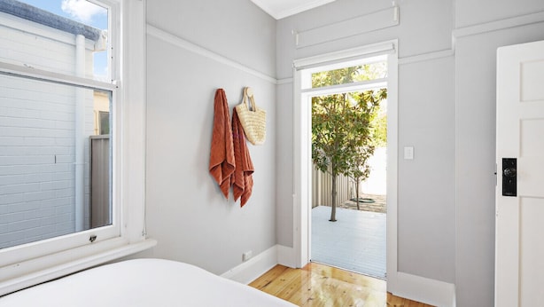Una habitación con una cama, una ventana, una puerta y vistas a un árbol fuera.