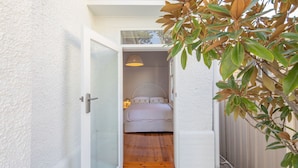 Un dormitorio con cama, lámpara colgante y piso de madera.