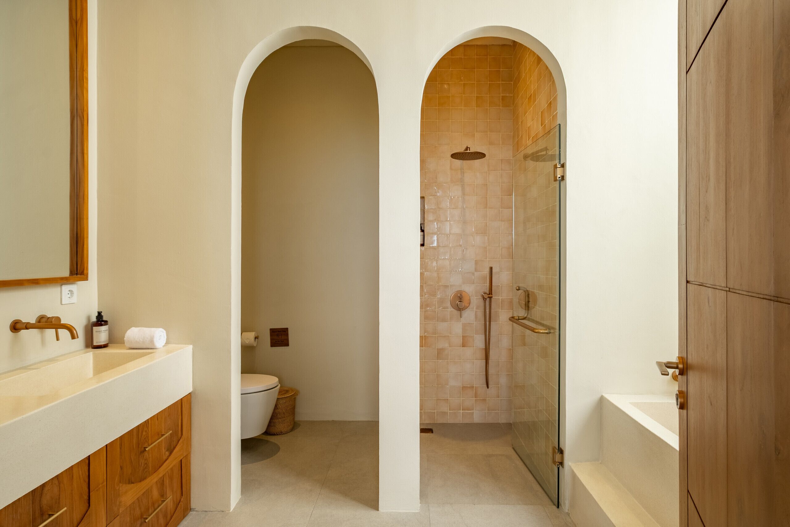 Un bagno moderno con un mobile lavabo in legno, una cabina doccia in vetro e un water.