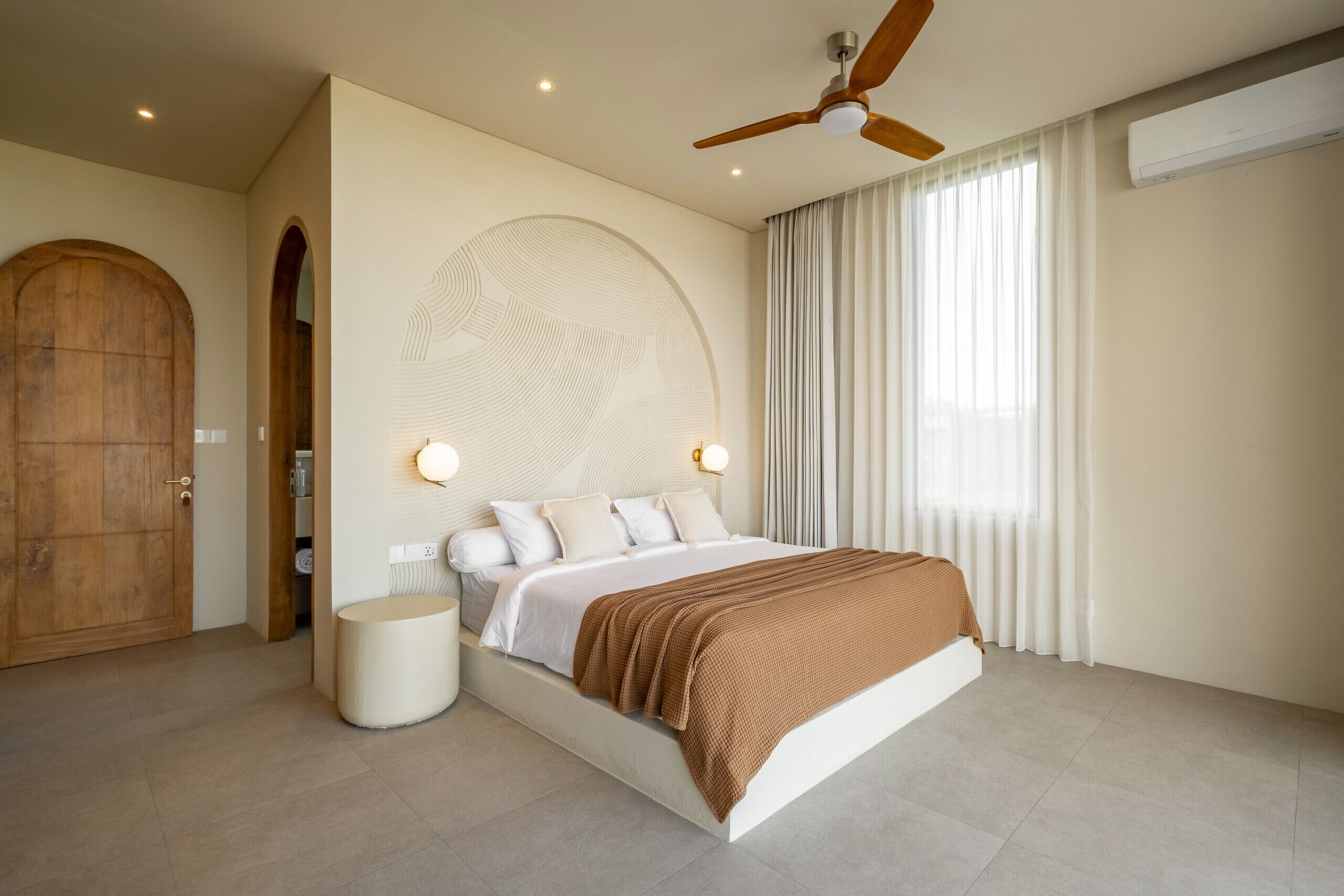 A modern bedroom with a large bed, a ceiling fan, and a large window with curtains.