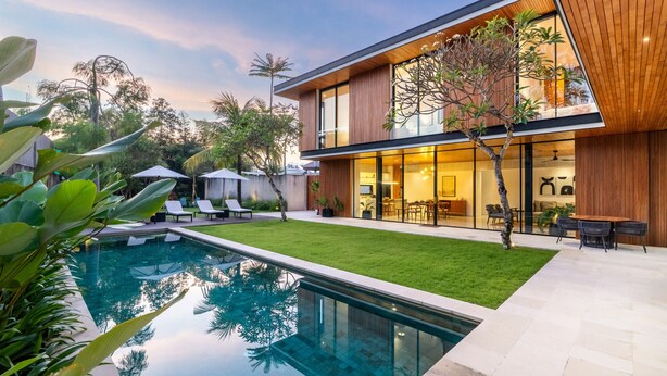 A modern two-story house with a swimming pool, outdoor seating, and a well-maintained lawn.