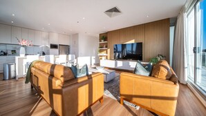 A modern living room with a sofa, a coffee table, and a TV. - The Views Penthouse - Cityscape & Parkland Scenery (Adelaide)