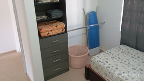 A bedroom with a bed, a wardrobe, a hanging rack, and a laundry basket. - Casa 2 recámaras zona aeropuerto clima total (Pesquería)