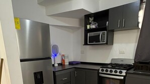 A kitchen with a refrigerator, microwave, stove, oven, and cabinets. - Casa 2 recámaras zona aeropuerto clima total (Pesquería)