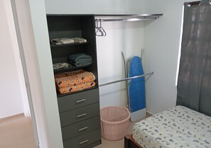 A bedroom with a bed, a wardrobe, a hanging rack, and a laundry basket. - Casa 2 recámaras zona aeropuerto clima total (Pesquería)