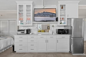 A modern kitchen with a built-in TV, stainless steel appliances, and white cabinetry. - Beach 2 Queen bed Studio Suite CoNdo (Palm Beach)