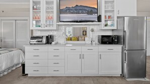Una cocina moderna con televisor integrado, refrigerador de acero inoxidable y muebles de color blanco.
