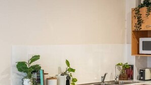 Una cocina moderna con encimera de mármol, taburetes de madera y un frutero.