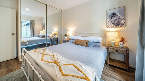 Un dormitorio con una cama grande, mesitas de noche, un espejo y un cuadro en la pared.