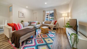 Una sala de estar moderna con sofá, sillón, reposapiés y televisor.
