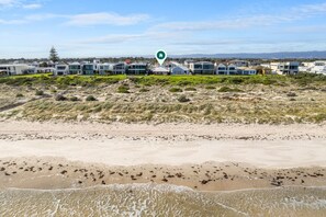 A coastal area with modern buildings, sandy beach, and a clear sky.
