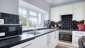 A modern kitchen with white cabinets, a black countertop, a built-in oven, and a window with a view of the outdoors.