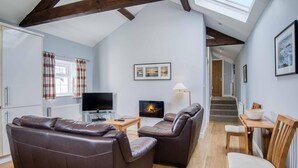 A cozy living room with a fireplace, leather sofas, a TV, and a dining area with a table and chairs.