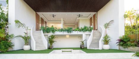 A modern house with a pool, two staircases, and a covered outdoor area with plants.