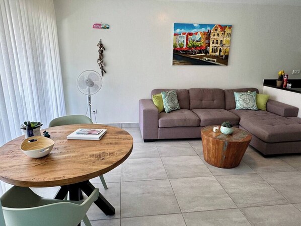 Un salon avec une table ronde en bois, un canapé et un tableau accroché au mur.