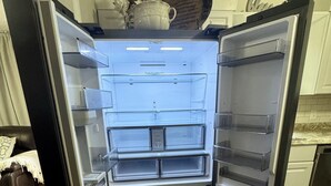 Une cuisine moderne dotée d’un réfrigérateur en acier inoxydable, de planchers en bois et d’armoires blanches.