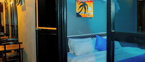 Una habitación de hotel con cama, un cuadro y una ventana con cortinas.