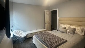Une chambre à coucher avec un lit, une chaise, un téléviseur et une porte.