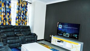 Ein modernes Wohnzimmer mit einem schwarzen Ledersofa, einem weißen Couchtisch und einem Flachbildfernseher, der an einem weißen und gelben Schrank befestigt ist.
