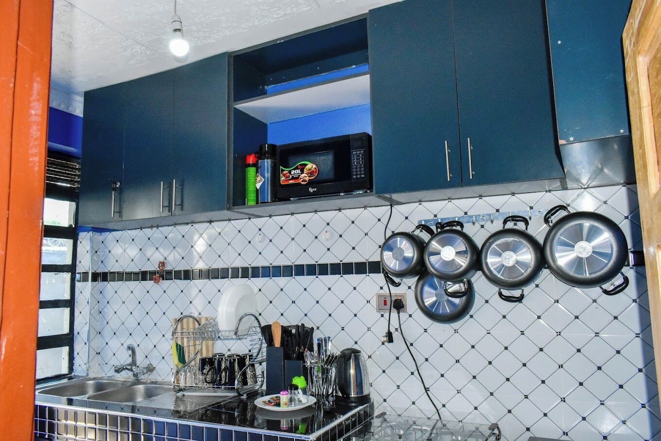 A kitchen with a microwave, stove, and hanging pots.