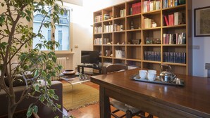 Ein gemütliches Wohnzimmer mit einer Holzbibliothek, einem Fernseher und einem Essbereich mit einem für Tee gedeckten Tisch.