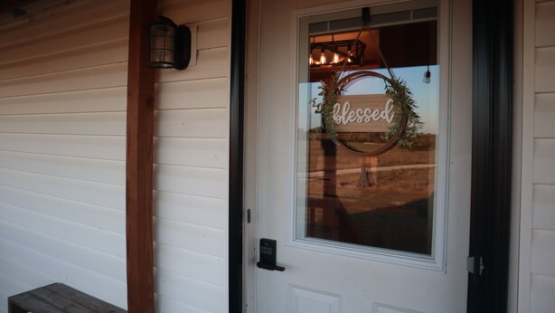 A white door with a glass panel, a wooden bench, and a wall-mounted light fixture.