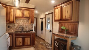 A kitchen with wooden cabinets, granite countertops, a sink, and a small dining area with a bench.