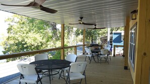 Eine überdachte Terrasse mit Tisch und Stühlen, Deckenventilatoren und Blick auf die Umgebung.