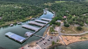 Una vista aerea di un porto turistico con barche ormeggiate, circondato da una fitta foresta e un fiume.
