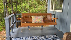 Un banco de madera con un cojín de colores sobre una terraza de madera.