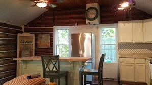Interior acogedor de una cabaña con comedor, cocina y ventana con vistas a follaje.