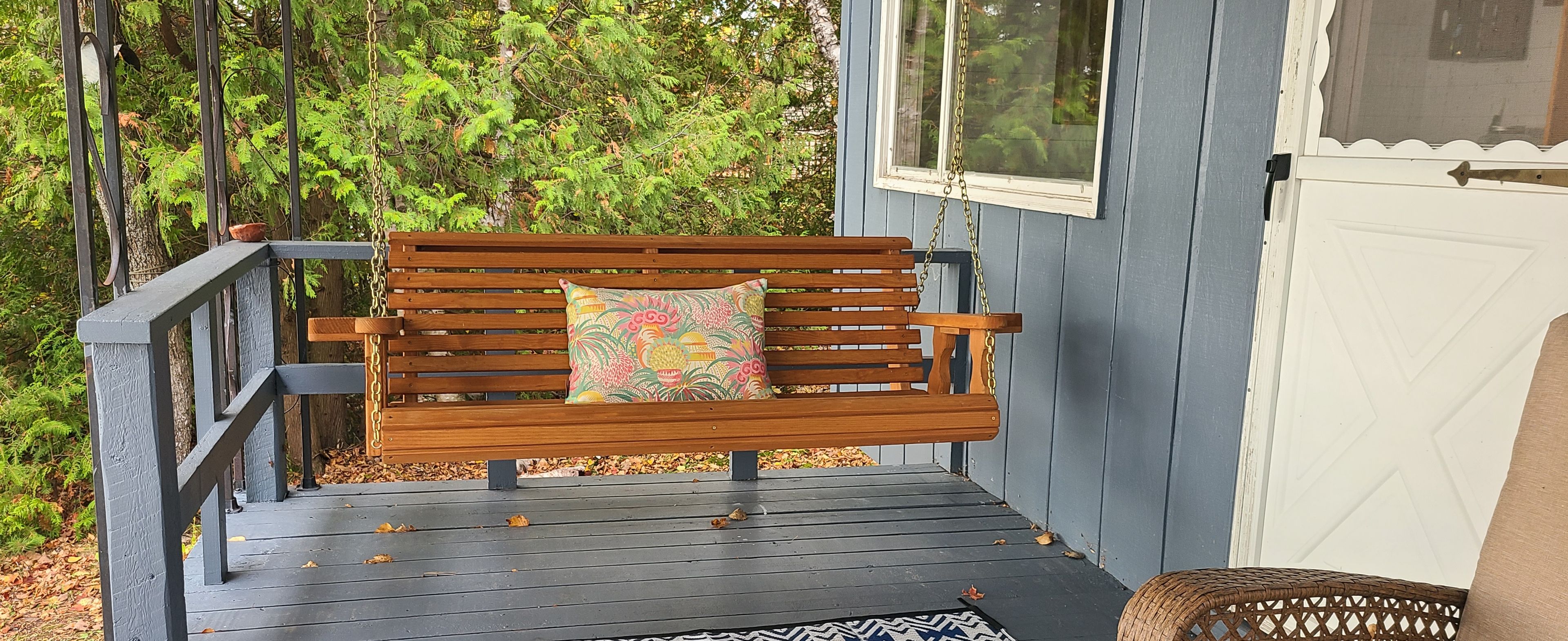 Un banc en bois avec un coussin coloré, placé sur une terrasse en bois.