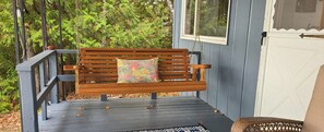 A wooden bench with a colorful cushion on a wooden deck.