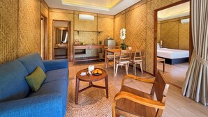 Une chambre d’hôtel comprenant un canapé, une table à manger avec des chaises, un petit coin cuisine et un lit.