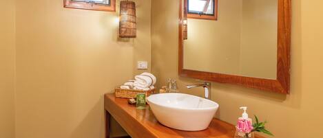 Un baño con tocador de madera, un espejo grande y un lavamanos blanco.