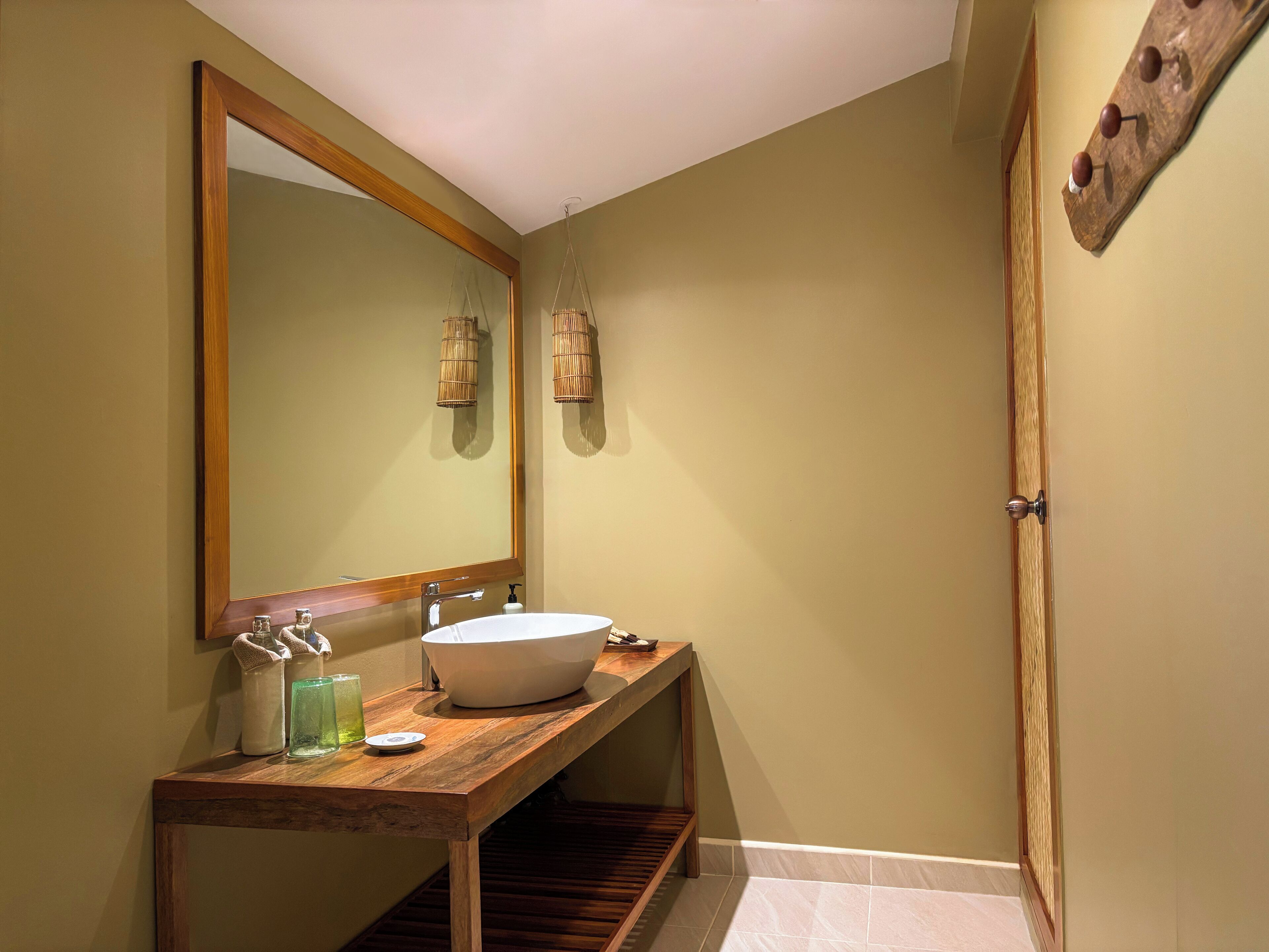 Un baño con tocador de madera, un espejo grande y un lavamanos blanco.