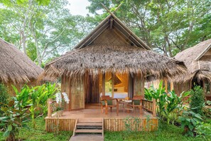 A thatched-roof hut with a wooden deck, surrounded by lush greenery. - The Riverfront Reserve (Pai)