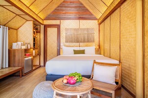 Una habitación con una cama, una pequeña mesa con fruta, un banco y un armario.