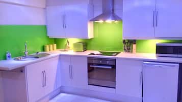 A modern kitchen with white cabinets, a green backsplash, a built-in oven, and a microwave.