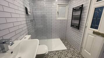 A bathroom with white subway tiles, a black and white patterned floor, a white door, and a towel rack.