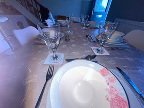 A dining table set with plates, glasses, and cutlery, with a staircase visible in the background.