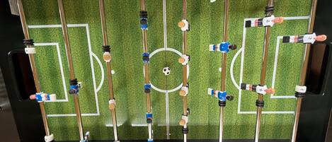 A foosball table with a soccer field layout, including goal areas and player figures.