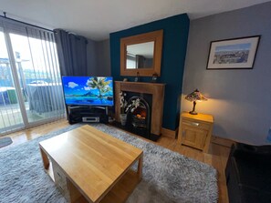 Ein Wohnzimmer mit Fernseher, Kamin und Blick durch eine Glastür.