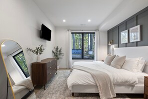 A modern bedroom with a bed, a dresser, a TV, and a window with curtains. - The Whispering Hollow – Private Pool, Hot Tub & Forest Escape Near Beach (Union Pier)