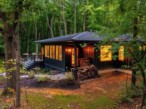Une cabane dotée d’une terrasse, entourée d’arbres.