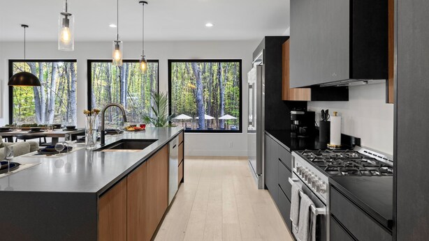 A modern kitchen with a large island, stainless steel appliances, and large windows with a forest view. - The Whispering Hollow – Private Pool, Hot Tub & Forest Escape Near Beach (Union Pier)
