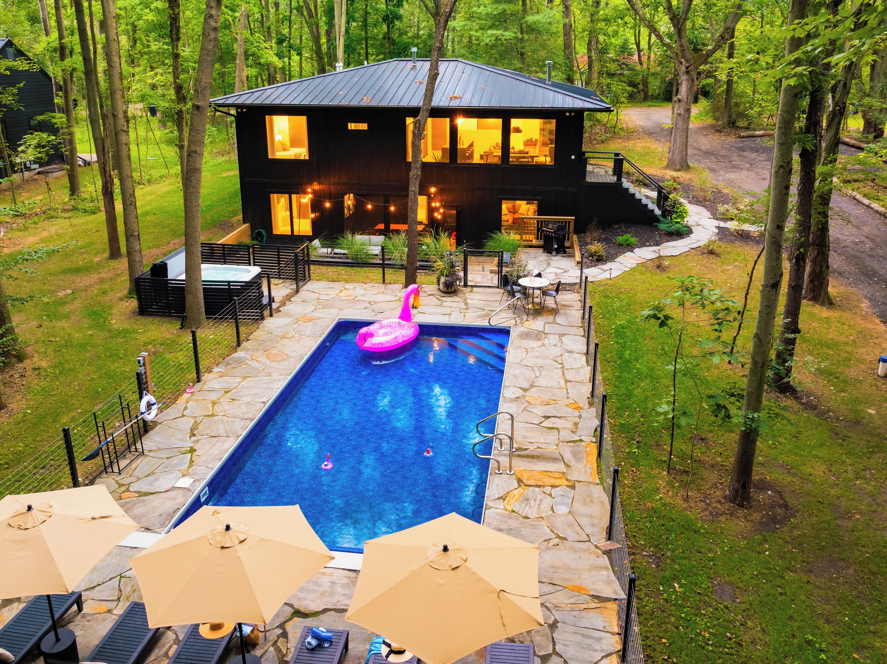 Una casa moderna con piscina, terraza de piedra y mobiliario exterior.