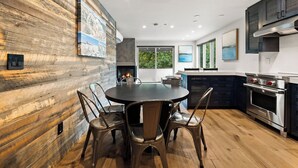 Een moderne keuken met een centraal eiland, houten wandbekleding en een open haard.