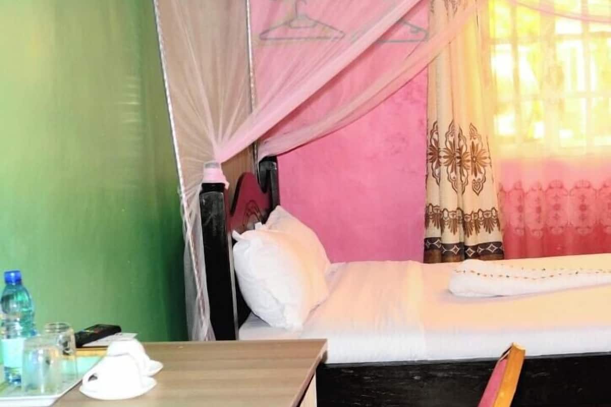 A room with a bed, a bedside table, a water bottle, and a cup.