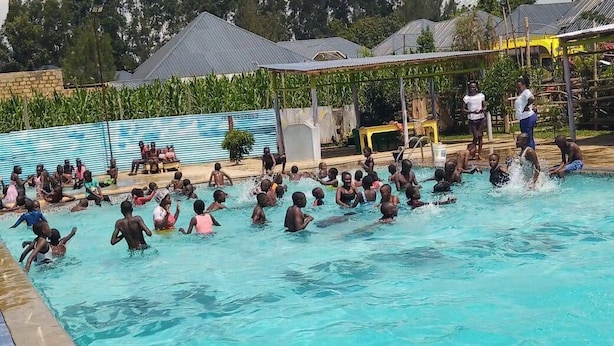 Una piscina con persone in acqua e a bordo.